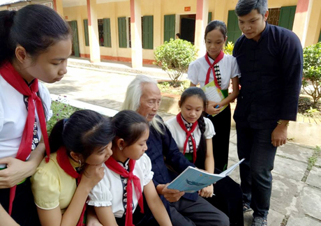 Nghệ nhân Lò Văn Biến cùng với thầy giáo Lê Thanh Tùng dạy chữ cho các em học sinh.